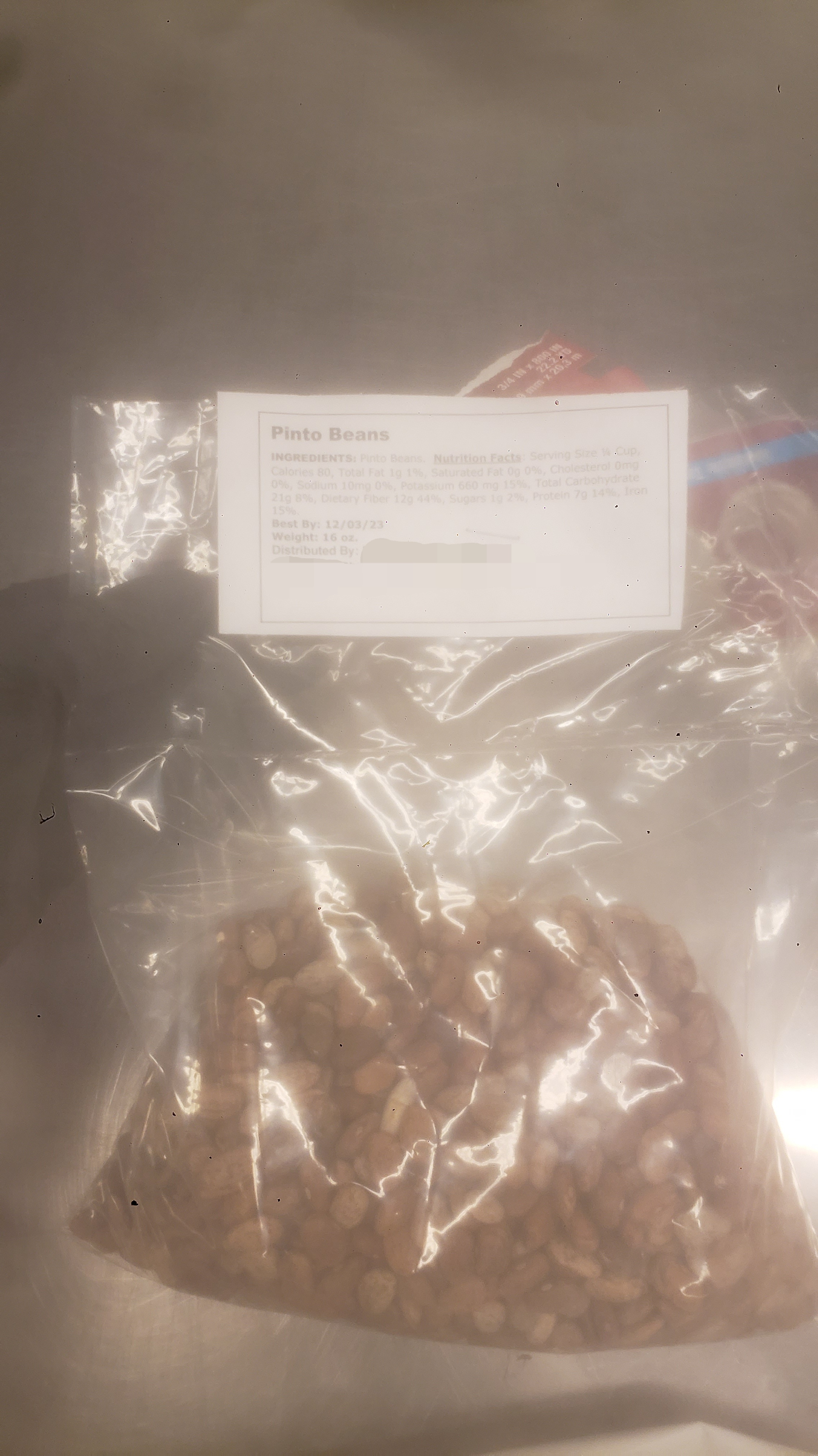 Bag of pinto beans with the food bank version of a label with ingredients, nutrition facts, and where it was distributed.